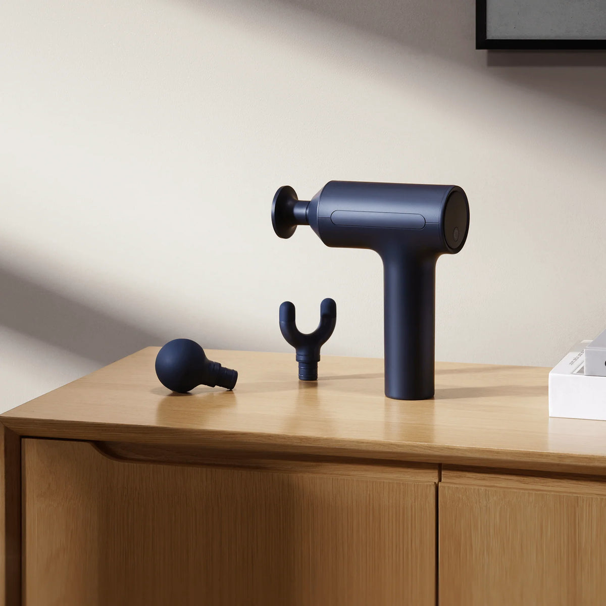 Xiaomi Massage Gun 2 op een houten kast met de ronde en de U-vormige opzetkop