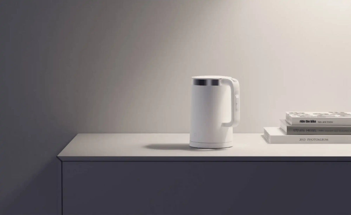 Witte Xiaomi waterkoker op een minimalistisch bureau naast boeken in een moderne interieur